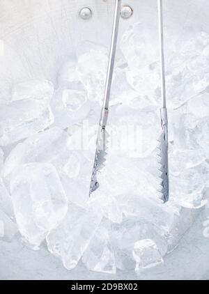Nahaufnahme des Eiswürfels und der Eiszange im Metalleimer für den Service für den Kunden im Restaurant. Stockfoto