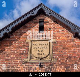 Pocklington, East Yorkshire, England, 03/11/2020 - Steinschild mit nationalen Schulen AD 1854 auf der Seite einer roten Ziegelmauer Stockfoto