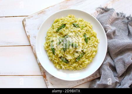 Italienisches Risotto mit Frühlingsspargel und Parmesankäse auf hellem Hintergrund. Draufsicht mit Kopierbereich. Stockfoto