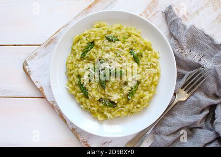 Italienisches Risotto mit Frühlingsspargel und Parmesankäse auf hellem Hintergrund. Draufsicht mit Kopierbereich. Stockfoto
