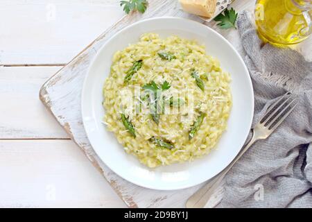 Italienisches Risotto mit Frühlingsspargel und Parmesankäse auf hellem Hintergrund. Draufsicht mit Kopierbereich. Stockfoto