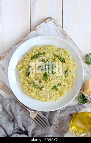 Italienisches Risotto mit Frühlingsspargel und Parmesankäse auf hellem Hintergrund. Draufsicht mit Kopierbereich. Stockfoto