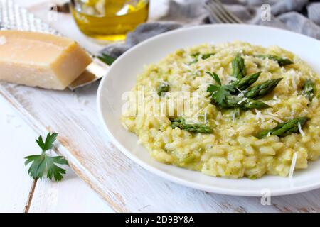 Italienisches Risotto mit Frühlingsspargel und Parmesankäse auf hellem Hintergrund. Draufsicht mit Kopierbereich. Stockfoto