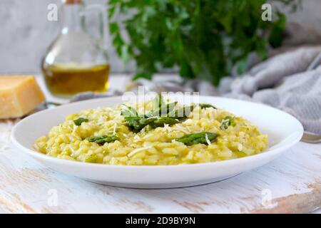 Italienisches Risotto mit Frühlingsspargel und Parmesankäse auf hellem Hintergrund. Draufsicht mit Kopierbereich. Stockfoto