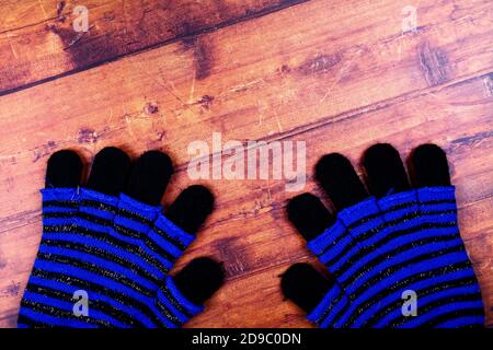 Blau und schwarz gestreifte Winterhandschuhe auf rustikalem Holz Hintergrund Stockfoto