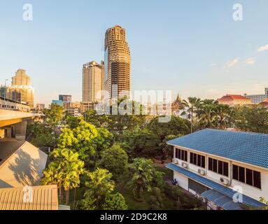 Urbane Szene. Verlassene Wolkenkratzer mit Grün beleuchtet von Golden Light in Bangkok, Thailand. Stockfoto