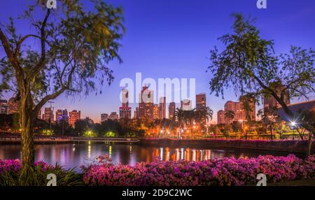 Lake in City Park unter Wolkenkratzern in der Nacht. Benjakiti Park in Bangkok, Thailand Stockfoto