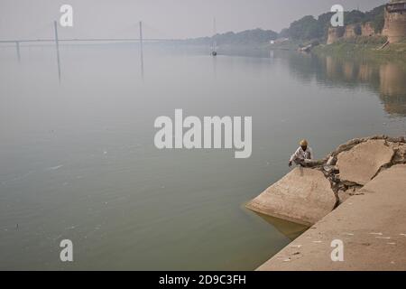 Allahabad, Indien, November 2015. Ein Mann, der entlang der Mauer des Forts an den Ufern des Yamuna Flusses in seiner Vereinigung mit dem Ganges fischt. Stockfoto