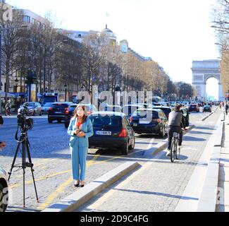 Paris, Frankreich. März 15. 2020. Journalist mit Mikrofon, der über die Champs Elysées berichtet. Triumphbogen im Hintergrund. Stockfoto