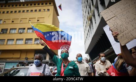 Caracas, Venezuela. November 2020. Ein Gesundheitshelfer schwenkt eine Flagge Venezuelas und ruft während eines Protestes mitten in der Corona-Pandemie Parolen. Ein Gewerkschaftsbündnis hatte den Protest für bessere Gehälter gefordert. Offiziellen Zahlen zufolge sind in Venezuela 93,100 Menschen an Covid-19 erkrankt und 810 Menschen daran gestorben. Die regierungstreuen Medien versichern, dass sich 94 Prozent der Corona-Virus-Patienten erholen werden. Demnach ist die Sterblichkeitsrate niedriger als in der Schweiz. Kredit: Rafael Hernandez/dpa/Alamy Live Nachrichten Stockfoto