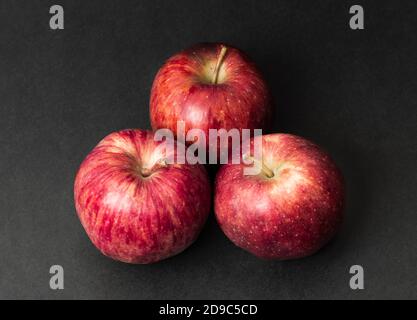 Drei ganze frische Apfelfrucht isoliert auf schwarzem Textur Hintergrund Stockfoto