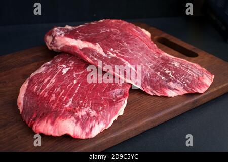 Zweiteiliges rohes Flankenrind auf einem Holzbrett auf Metzgerei, frisches Premium-Fleisch schwarzer angus auf dem Tisch Stockfoto