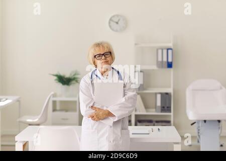 Porträt eines erfahrenen Oberarztes, der die Kamera im Stehen betrachtet Krankenhausbüro Stockfoto
