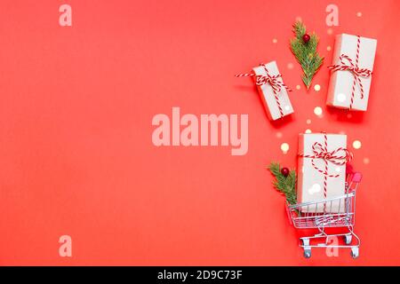 Warenkorb mit Geschenken auf weihnachtlich rotem Hintergrund mit Kopierplatz. Stockfoto