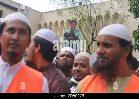 Dhaka, Bangladesch. Oktober 2020. Ein Plakat des französischen Präsidenten Macron ist im Hintergrund der Demonstranten zu sehen, auf dem Schuhe aufgeklebt sind.die Islami Andolon, eine der größten islamistischen Parteien Bangladeschs, Einen protestmarsch abhalten, der zum Boykott französischer Produkte aufruft und den französischen Präsidenten Emmanuel Macron für seine Bemerkungen anprangert: "˜die Karikaturen des Propheten Mohammed nicht aufgeben". Macrons Bemerkungen kamen als Reaktion auf die Enthauptung eines Lehrers, Samuel Paty, außerhalb seiner Schule in einem Vorort außerhalb von Paris Anfang dieses Monats, nachdem er Karikaturen des Propheten Mohammed während gezeigt hatte Stockfoto