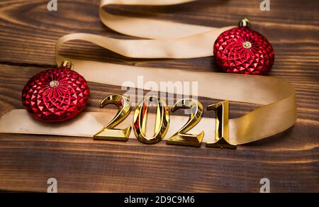 Ein Weihnachtsbaum aus Goldband mit den Zahlen 2021 ist mit roten Ballons auf dunklem Holzhintergrund verziert. Flach liegend. Leerzeichen für Text. Neu y Stockfoto