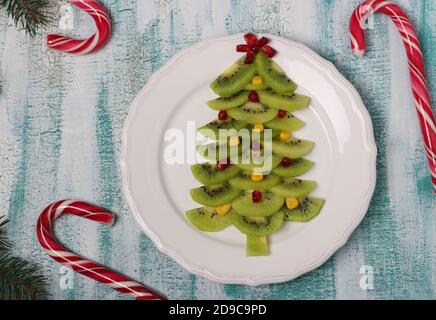 Weihnachtsbaum aus Kiwi, Mais und Granatapfel, kreative Idee für Weihnachten und Silvester festliche Gerichte, Obstsnack für Kinder. Draufsicht Stockfoto