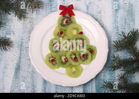 Weihnachtsbaum aus Kiwi und Granatapfel, kreative Idee für Weihnachten und das neue Jahr festlich Speisen, Obst Snack für Kinder Stockfoto