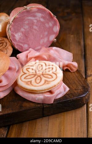 Big Mortadella und Tigelle auf einem Holztisch. Verschiedene Brotsorten, für traditionelle italienische Sandwiches in der Region Emilia Romagna. Oben. Speicherplatz kopieren Stockfoto