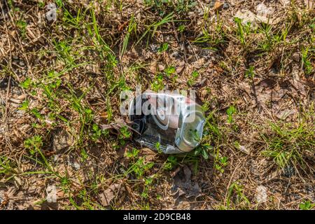 Eine Coca-Cola mit Eisbären-Grafiken leer und zerknittert weggeworfen Achtlos auf dem Boden im Gras entlang der Autobahn Die Umwelt verschmutzen Stockfoto