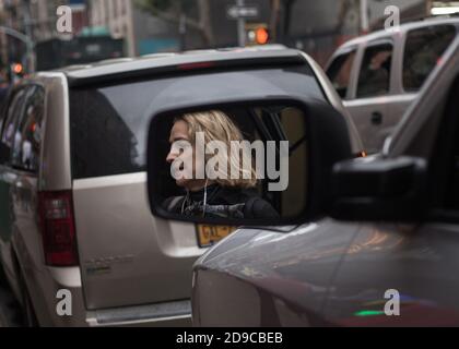 Das Gesicht einer Person auf dem Seitenspiegel eines Autos an einem anstrengenden Tag gefangen. USA Stockfoto