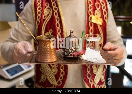 Ein Mann serviert ein Tablett mit traditionellen türkischen Kaffee auf dem Sand in Turku, selektive Fokus. Stockfoto