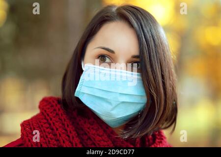 Schöne junge Frau in medizinischen Schutz Gesichtsmaske zu Fuß im Freien im Herbst Park. Coronavirus-Lockdown-Konzept. Stockfoto