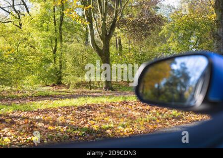 Autospiegel Nahaufnahme mit schöner Herbstlandschaft in Reflexion, auf der Straße mit dem Auto auf leerer Straße verschwommener Hintergrund Stockfoto