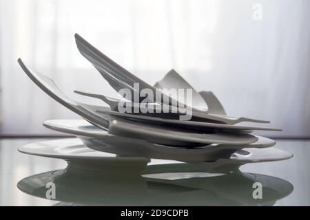 Haufen zerbrochener weißer Teller auf einem Glastisch Stockfoto