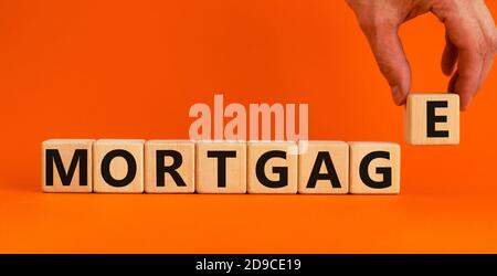 'Mortgage' auf Holzblöcken geschrieben. Männliche Hand. Geschäftskonzept. Speicherplatz kopieren. Schöner orangefarbener Hintergrund. Stockfoto