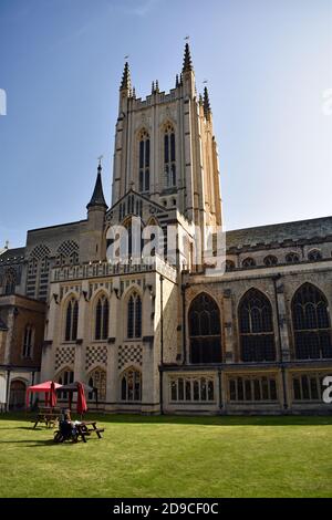 St Edmundsbury Cathedral in Bury St Edmunds, Suffolk, England. Picknicktische, rote und schwarze Pavillons und rote Schirme befinden sich auf dem Graskirchhof. Stockfoto