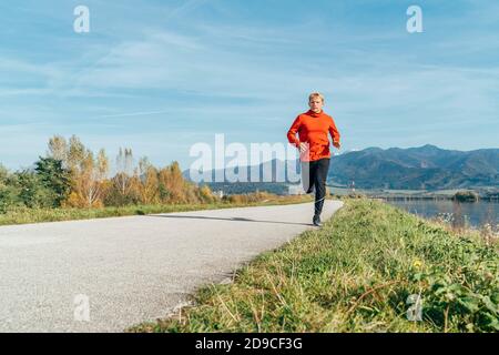 Mann in roten Langarm-Shirt an der Asphaltstraße mit Berg Hintergrund gekleidet. Sportliche Menschen Aktivitäten und ein gesundes Lifestyle-Konzept im Stockfoto