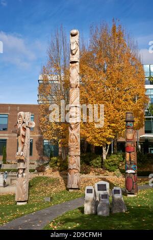 Kwakiutl style Versöhnung Totem Pol und Küste Salish Willkommen Beiträge außerhalb der Vancouver School Board Building, Vancouver, BC, Kanada Stockfoto