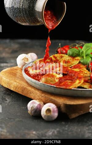 Ravioli mit Tomatensauce und Basilikum auf dunkel Stockfoto