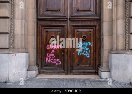 Protestgraffiti in der Via Laietana in spanischer und katalanischer Sprache, die den Reichen Krieg sagen, gemalt an der Tür eines Hochhauses während der Krise. Stockfoto