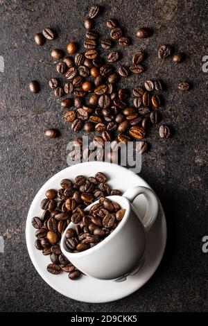 Geröstete Kaffeebohnen in Tasse auf schwarzem Tisch. Draufsicht. Stockfoto