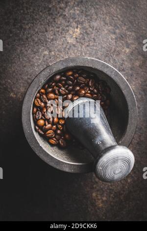 Geröstete Kaffeebohnen in Mörtel auf schwarzem Tisch. Draufsicht. Stockfoto