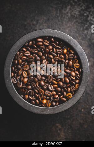 Geröstete Kaffeebohnen in Schüssel auf schwarzem Tisch. Draufsicht. Stockfoto