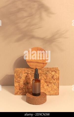 Braunglasflasche aus Bio-Naturkosmetik mit beigefarbenem Naturdekor. Serum oder ätherisches Öl osmetisch. Monochrome kreative Komposition mit Schatten Stockfoto