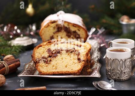 Weihnachtskuchen mit Nüssen, bedeckt mit Puderzucker auf dem weihnachtlichen Hintergrund. Nahaufnahme Stockfoto