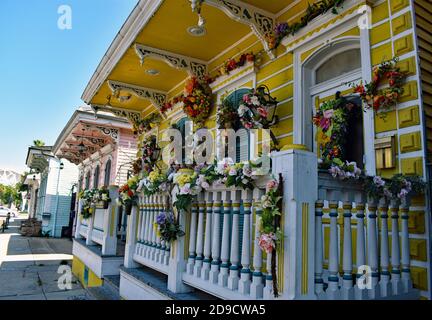 Ein traditionelles gelbes kreolisches Cottage in der St Ann Street im historischen French Quarter in New Orleans, Louisiana. Blumen schmücken die Veranda und Balustrade. Stockfoto