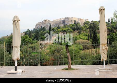 Griechenland, Athen, 3. November 2020 - geschlossene Schirme des leeren Cafe-Restaurants mit Akropolis-Hügel im Hintergrund, nach der Ankündigung für Covid-19 Stockfoto