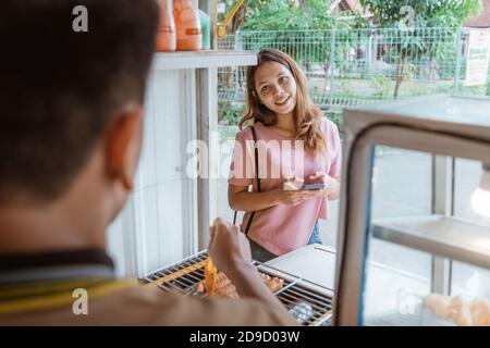 Frau wartet auf gegrilltes Wurstfutter, das gerade zubereitet wird Durch den Mann Stockfoto