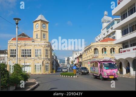 Blick auf die Altstadt von Phuket Town im Süden Thailands, mit dem Wahrzeichen, ikonischen alten Uhrturm in der b/g und einem lokalen Pink Bus (Potong) rechts Stockfoto