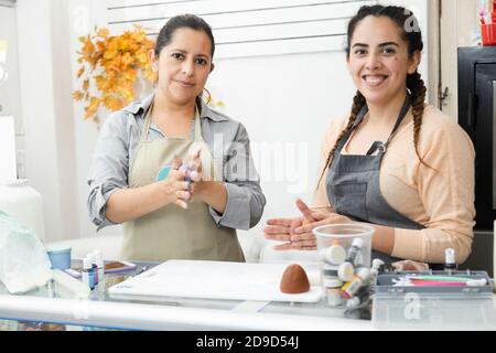 Lateinische Frauen, die in ihrer Bäckerei arbeiten - Frauen Konditorinnen Arbeiten mit Fondant, um einen Kuchen zu dekorieren - hispanische Frauen Unternehmer Stockfoto