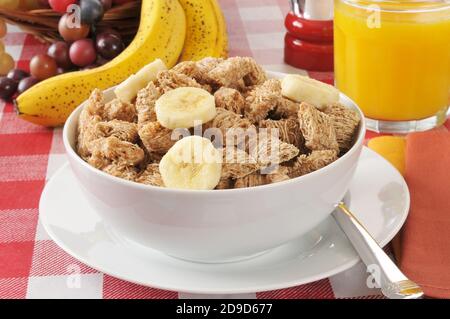 Eine Schüssel zerfetztes, organisches Weizengetreide mit Bananenscheiben Stockfoto