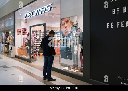 Valencia, Spanien. November 2020. Ein Mann, der eine Gesichtsmaske trägt und die Kleidung im Decimas-Laden im Osito La Eliana Einkaufszentrum betrachtet. Kredit: Xisco Navarro/SOPA Images/ZUMA Wire/Alamy Live Nachrichten Stockfoto