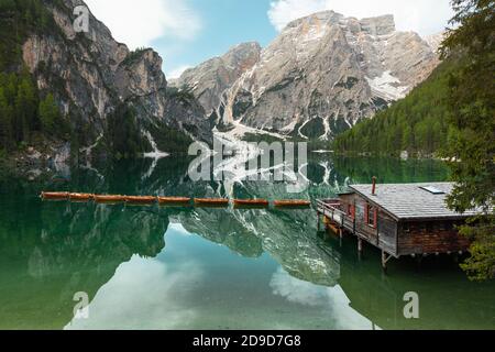 Hochwinkelansicht von ikonischem Bootshaus und Booten mit dem Seekofel-Berg, der sich im klaren, ruhigen Wasser des Pragser Wildsee (Pragser Pragser See) in den Dolomiten spiegelt, Stockfoto