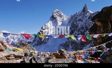 Farbenfrohe buddhistische Gebetsfahnen winken friedlich im kalten Wind auf dem Gipfel des Renjo La Passes, Himalaya, Nepal mit eisbedeckten Bergen. Stockfoto