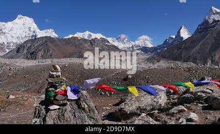 Farbenfrohe buddhistische Gebetsfahnen, die an einen Steinhaufen gebunden sind und im kalten Wind im oberen Gokyo-Tal, im Sagarmatha-Nationalpark, Nepal, fliegen. Stockfoto